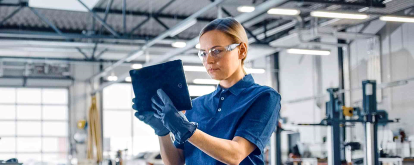 Industrial maintenance technician using a tablet on a factory floor to manage CMMS work orders in real time, demonstrating mobile workforce enablement for successful EAM implementation